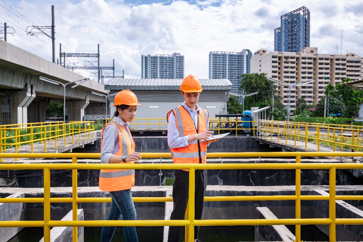 Engineers inspecting and monitoring operations at a wastewater treatment facility with industrial water processing tanks.