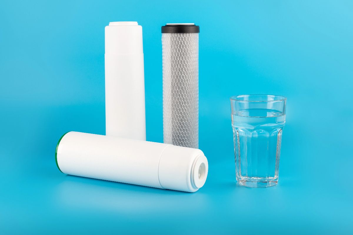 Reverse osmosis filter cartridges and a glass of clear water on a blue background