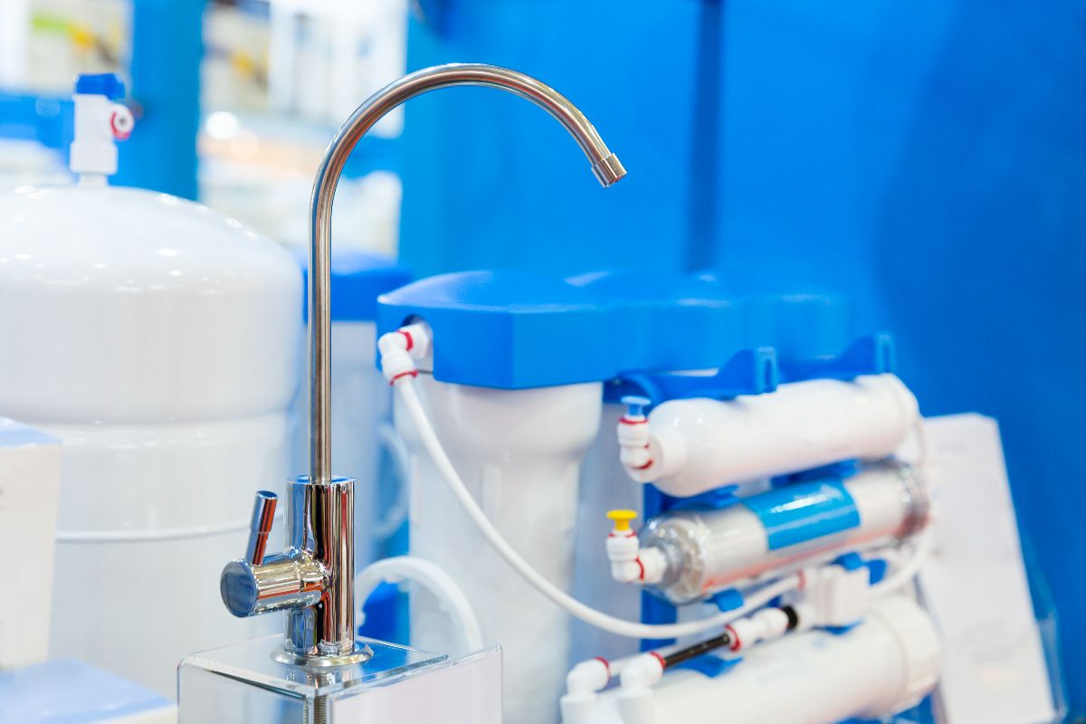 Reverse osmosis water filtration unit with a chrome faucet, storage tank, and blue-and-white filter components