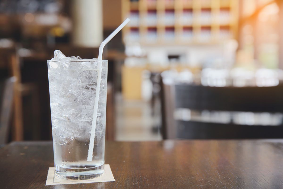 Glass of iced beverage with a straw on a restaurant table, representing purified water used for drinks and ice production
