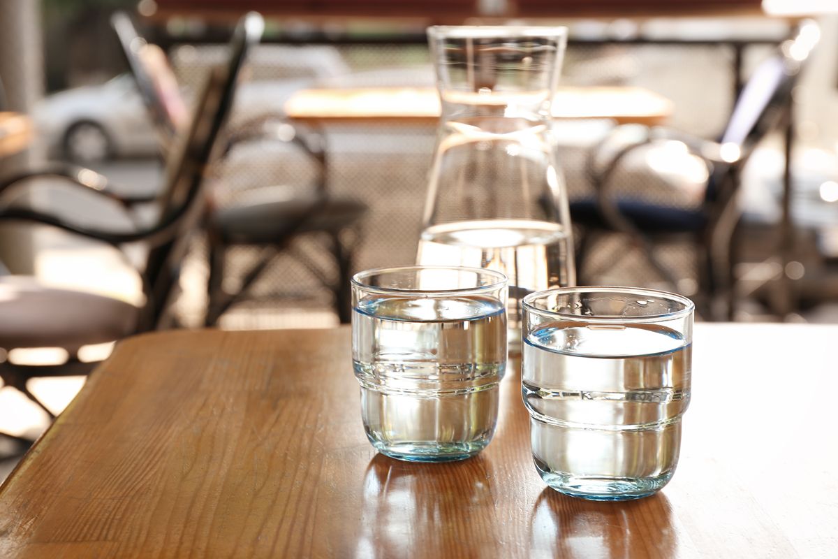 Glasses and a carafe of water on a cafe table, showing daily purified water demand in food and beverage service