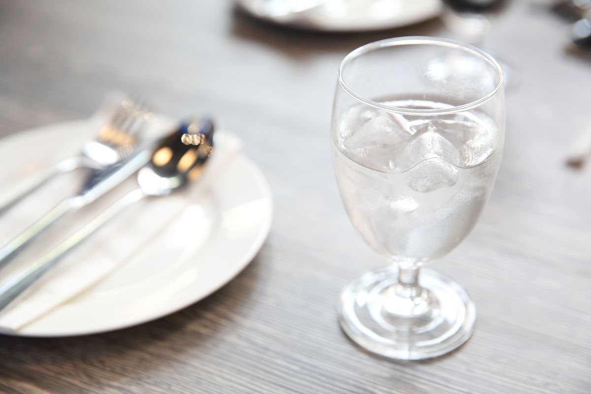 Glass of iced water on a restaurant table, representing water quality needs for cafe drinks and ice service