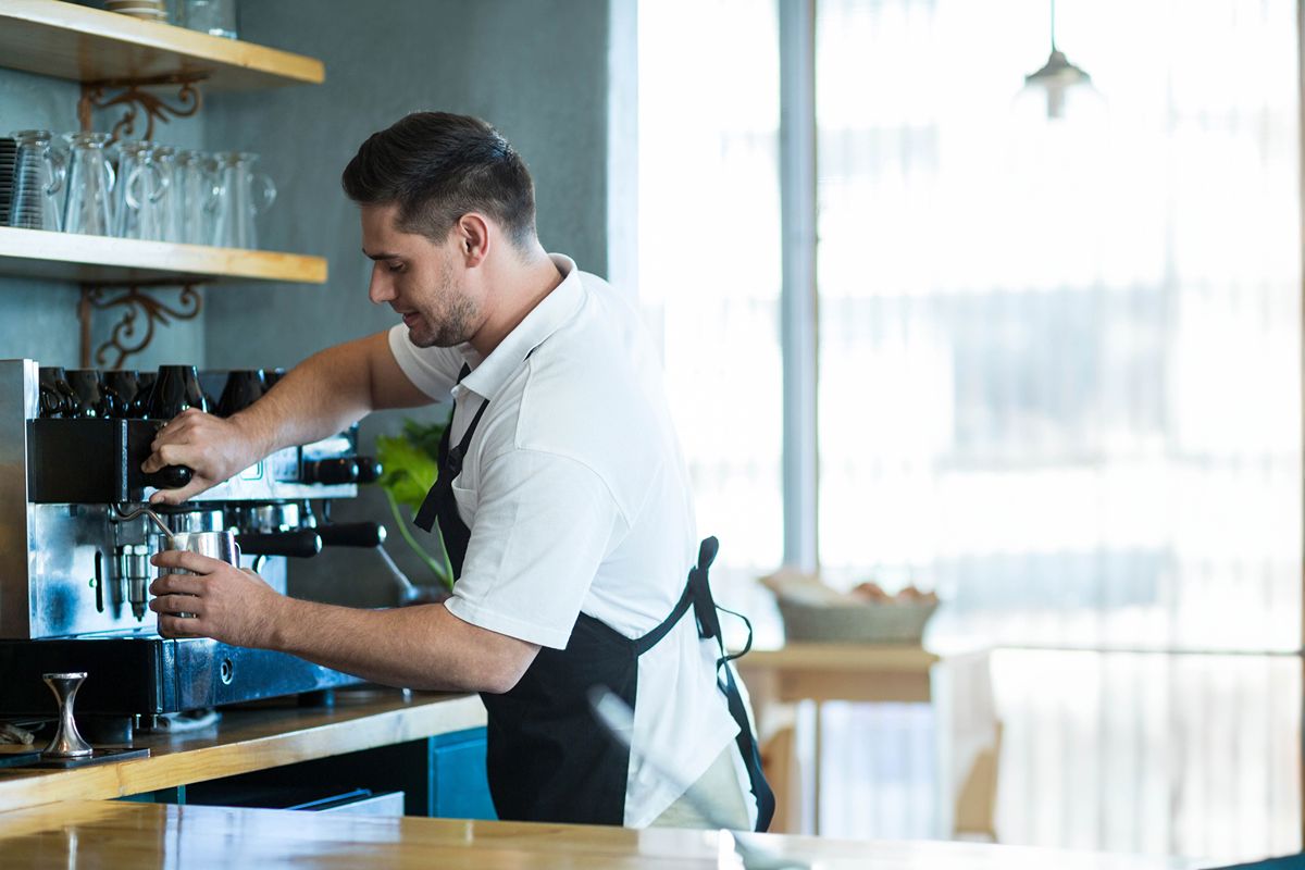 Staff member preparing a drink with a coffee machine, representing consistent beverage flavor across fast-food branches
