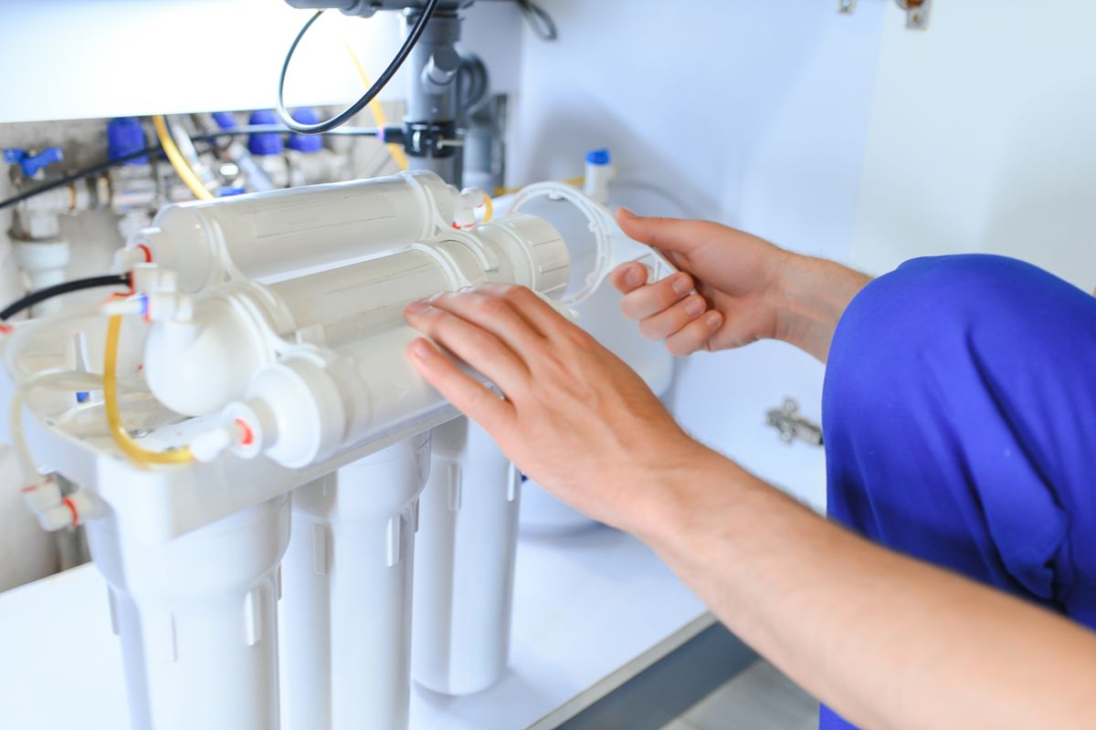 Technician servicing an under-sink reverse osmosis filtration system for reliable fast-food water treatment
