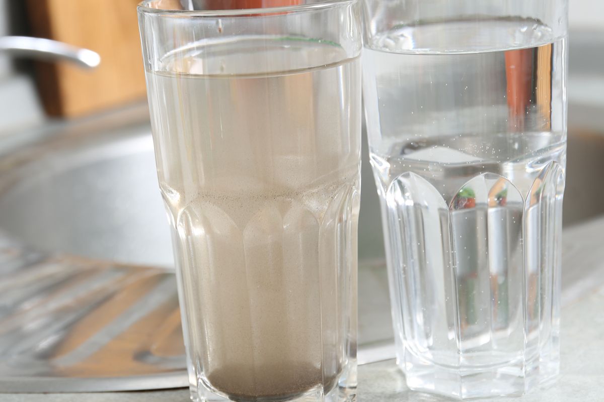 Cloudy glass of water beside a clear glass, showing visible signs of possible drinking water contamination