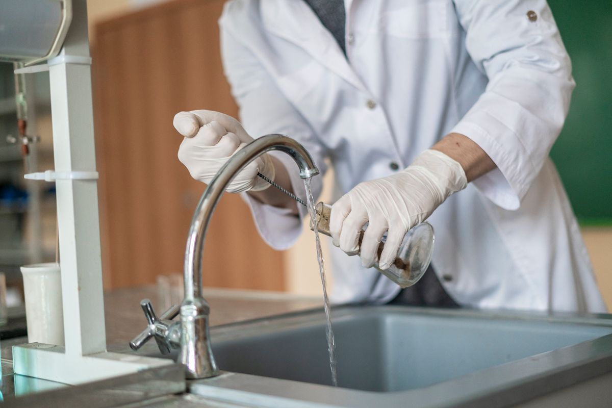 Hospital staff member washing medical equipment at a sink, representing water quality for sterilization processes