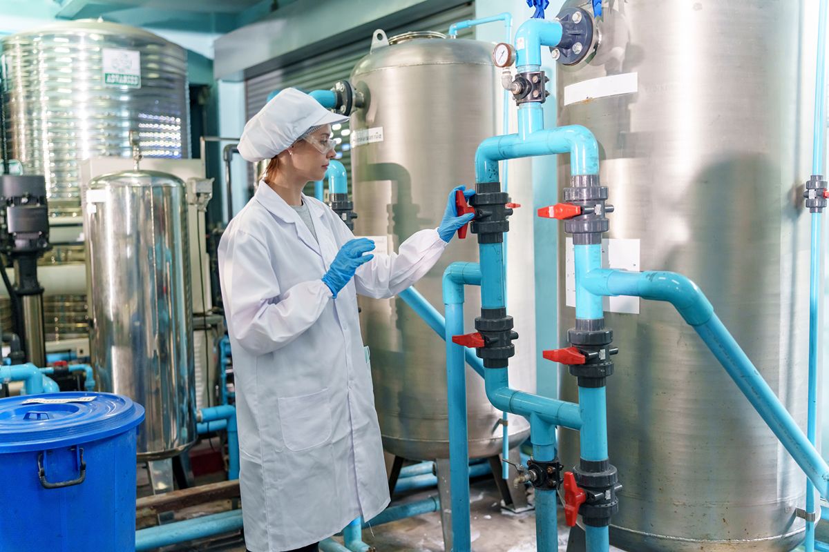 Technician inspecting water treatment pipes and tanks inside a hospital filtration facility