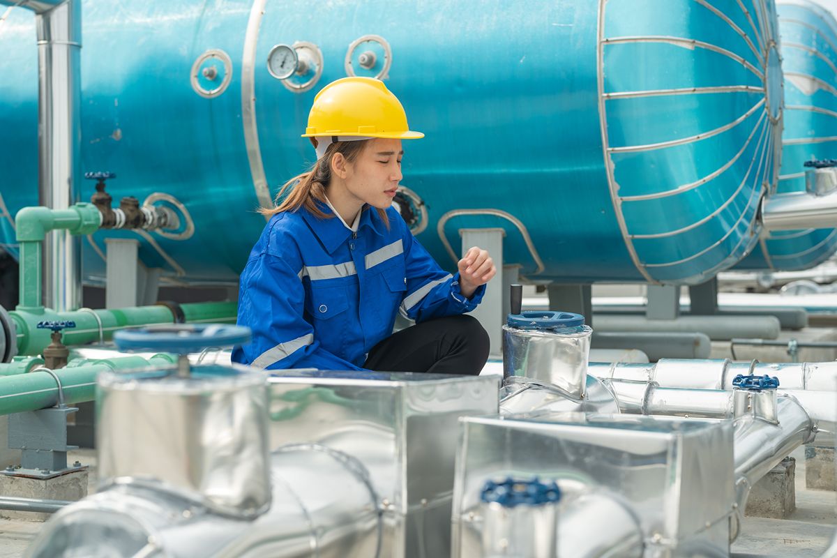 Technician inspecting blue water treatment tanks and piping for RO system operational planning